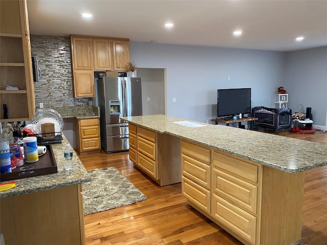 kitchen featuring tasteful backsplash, a kitchen island, recessed lighting, light wood-style flooring, and stainless steel refrigerator with ice dispenser