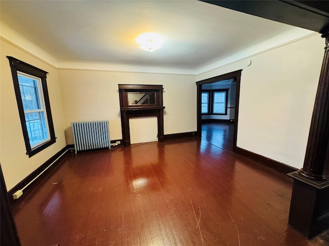 spare room with dark wood-type flooring and radiator heating unit