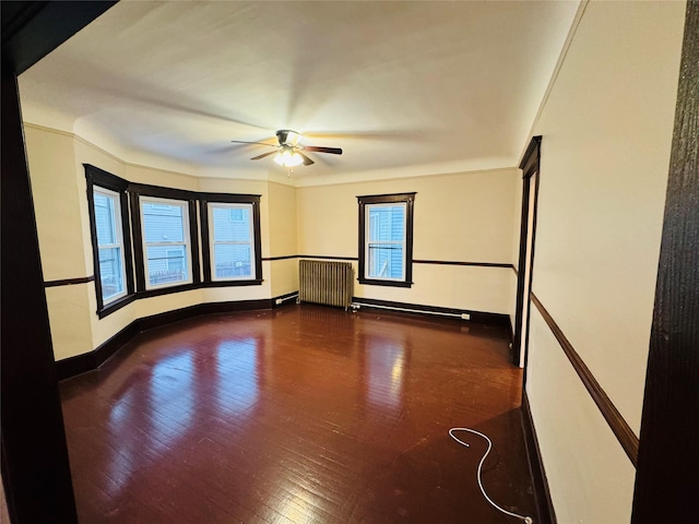 unfurnished room with dark hardwood / wood-style floors, crown molding, radiator, and ceiling fan