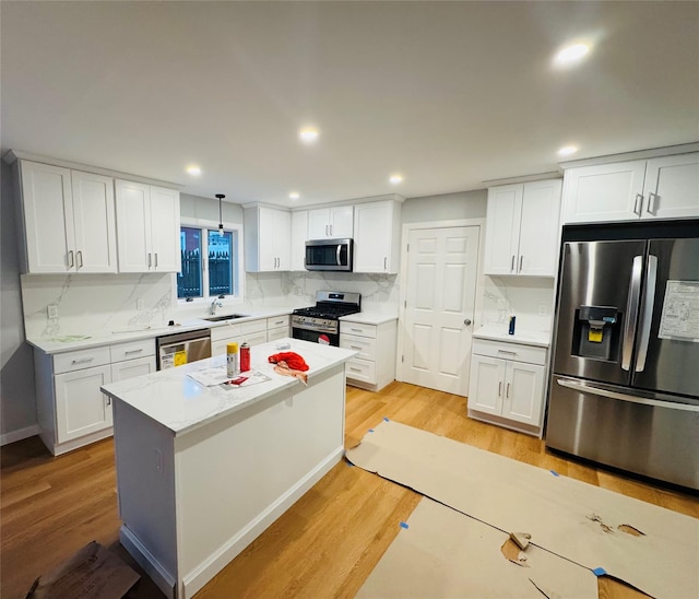 kitchen with appliances with stainless steel finishes, sink, pendant lighting, and white cabinets