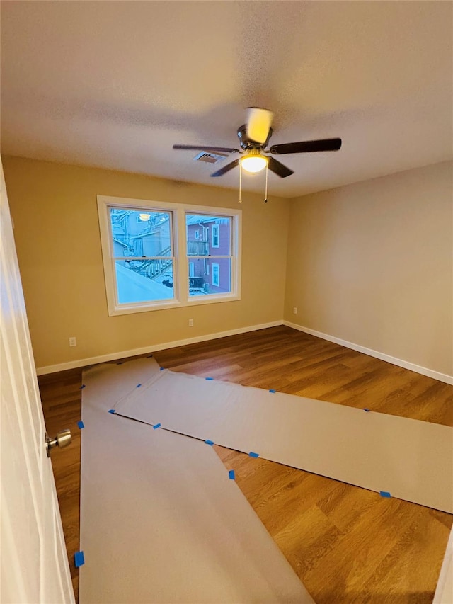 empty room with hardwood / wood-style flooring, a textured ceiling, and ceiling fan