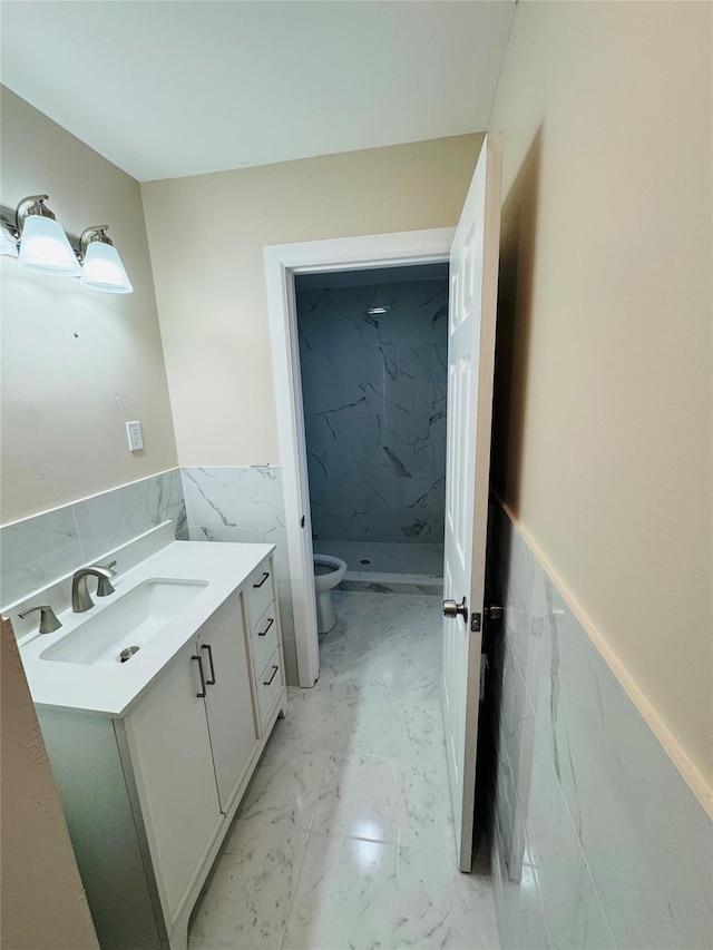 bathroom with vanity, a tile shower, tile walls, and toilet