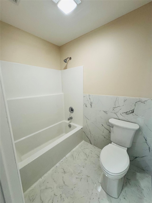 bathroom featuring bathtub / shower combination, toilet, and tile walls