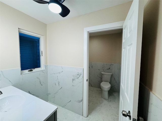 bathroom with vanity, tile walls, ceiling fan, and toilet