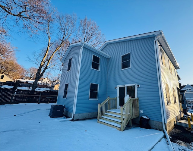 snow covered rear of property featuring central air condition unit