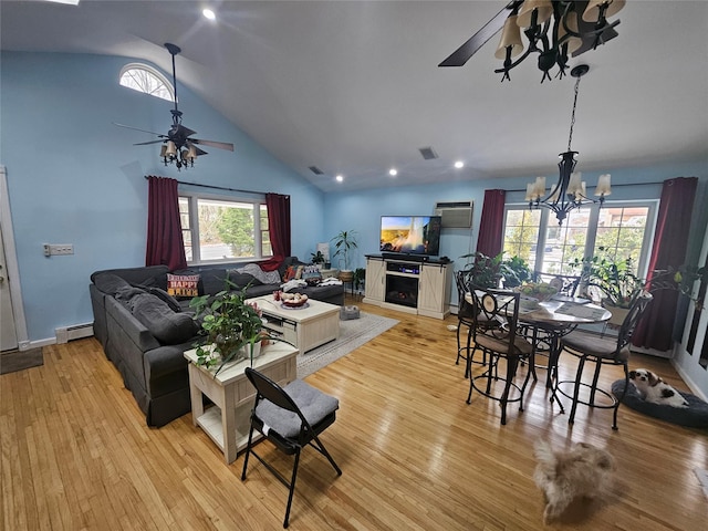 living room featuring lofted ceiling, ceiling fan with notable chandelier, plenty of natural light, and light hardwood / wood-style flooring