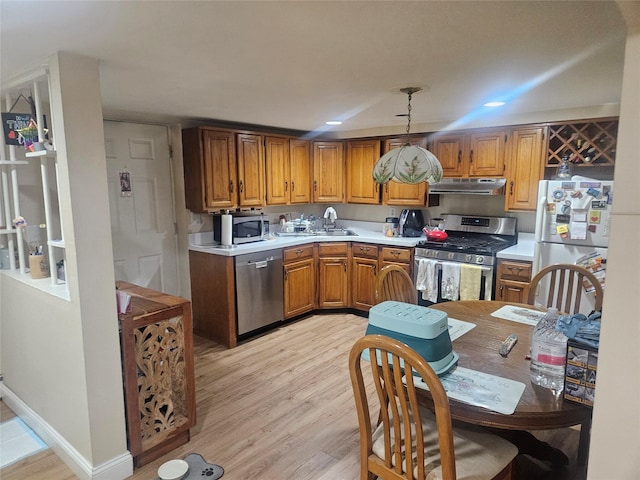 kitchen with sink, decorative light fixtures, light hardwood / wood-style flooring, and appliances with stainless steel finishes