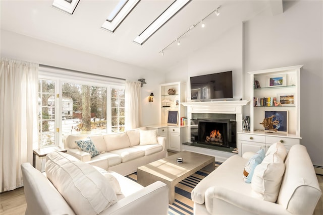 living room with high vaulted ceiling, a skylight, and light hardwood / wood-style floors