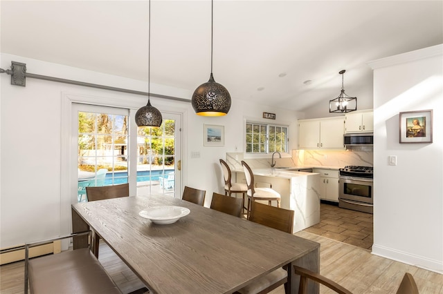 dining space with vaulted ceiling, sink, light wood-type flooring, and a wealth of natural light