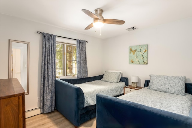 bedroom with a baseboard heating unit, ceiling fan, and light hardwood / wood-style flooring