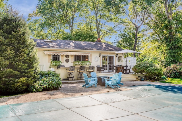 rear view of property featuring a patio area and exterior bar