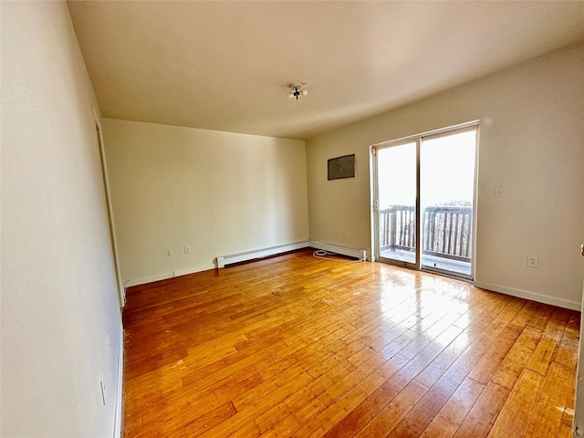 unfurnished room featuring a baseboard heating unit, light wood finished floors, and baseboards