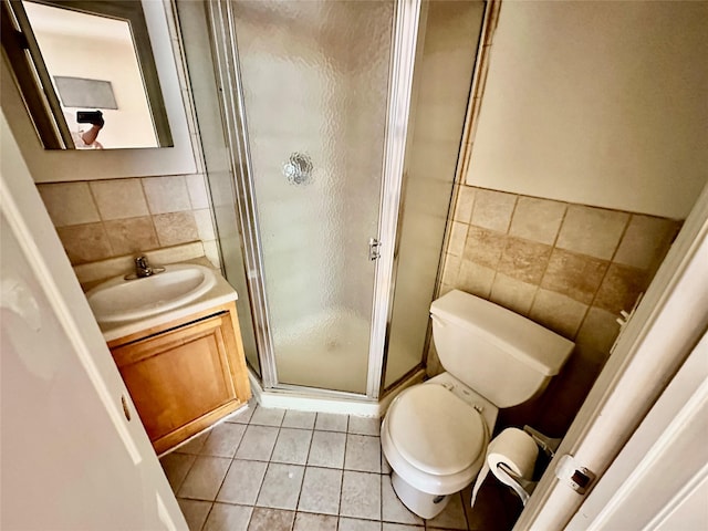 full bathroom with tile walls, toilet, vanity, a shower stall, and tile patterned floors