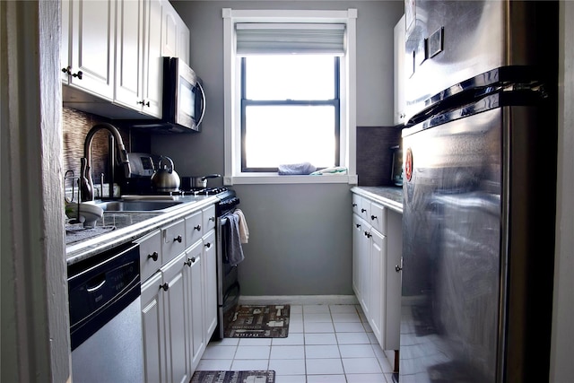 kitchen featuring sink, light tile patterned flooring, white cabinets, and appliances with stainless steel finishes