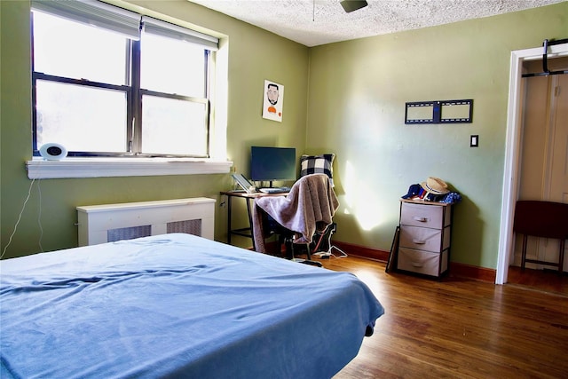 bedroom with multiple windows, ceiling fan, hardwood / wood-style floors, and a textured ceiling