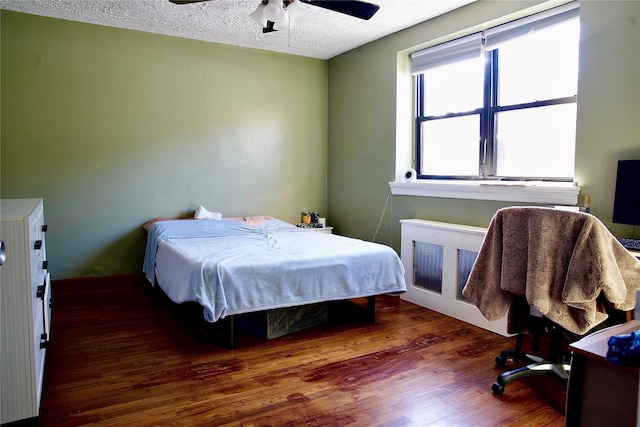 bedroom with dark hardwood / wood-style floors, a textured ceiling, and ceiling fan