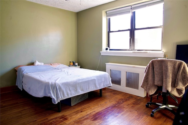 bedroom with radiator, dark hardwood / wood-style floors, and a textured ceiling