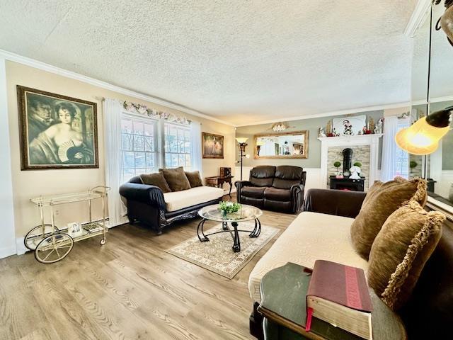 living room featuring crown molding, a textured ceiling, and light wood-type flooring