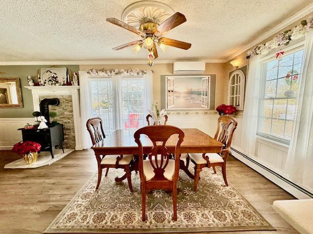 dining room with a wood stove, a wall mounted AC, hardwood / wood-style flooring, a baseboard heating unit, and a textured ceiling