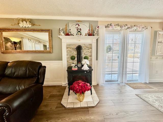 sitting room with hardwood / wood-style flooring, ornamental molding, a textured ceiling, and a wood stove