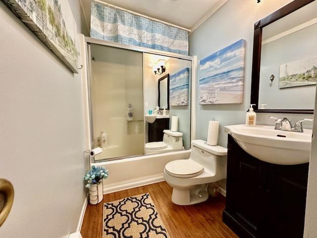 full bathroom featuring toilet, vanity, ornamental molding, enclosed tub / shower combo, and hardwood / wood-style floors