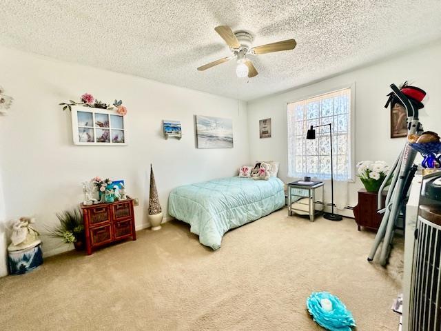 bedroom with a textured ceiling, carpet floors, and ceiling fan