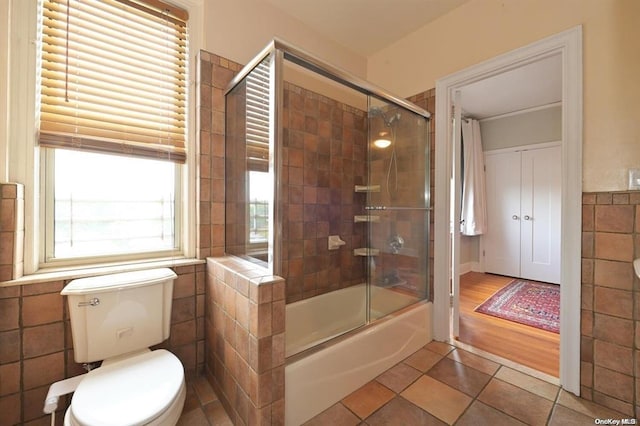 bathroom with tile patterned floors, toilet, and combined bath / shower with glass door