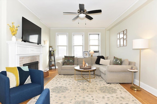 living room featuring hardwood / wood-style flooring, crown molding, a brick fireplace, and ceiling fan