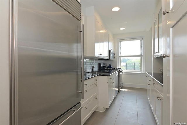 8 Barstow Rd Unit 7-E, Great Neck, NY 11021 - kitchen with stainless steel appliances, white cabinetry, light tile patterned flooring, recessed lighting, and decorative backsplash