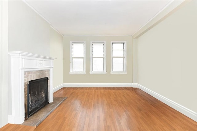 8 Barstow Rd Unit 7-E, Great Neck, NY 11021 - unfurnished living room with a brick fireplace, ornamental molding, and light wood-style flooring