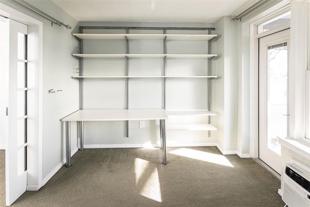 interior space with a wall mounted AC, dark carpet, and baseboards