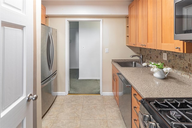 kitchen with light stone counters, light tile patterned floors, stainless steel appliances, backsplash, and a sink