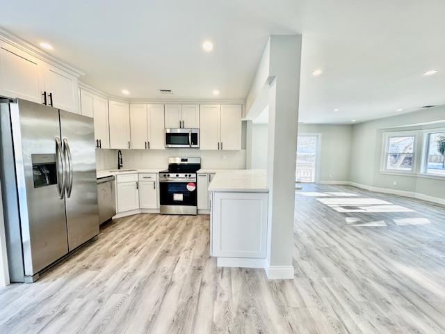 kitchen with white cabinetry, appliances with stainless steel finishes, sink, and light hardwood / wood-style flooring