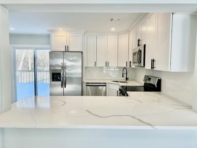 kitchen featuring white cabinetry, appliances with stainless steel finishes, sink, and light stone counters