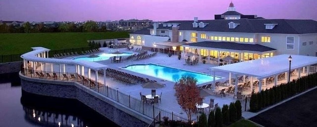 pool at dusk with a water slide and a patio area