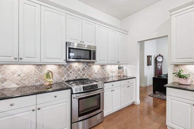 kitchen with decorative backsplash, light wood-type flooring, white cabinets, and appliances with stainless steel finishes