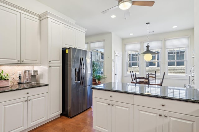 kitchen featuring tasteful backsplash, white cabinetry, stainless steel fridge, hanging light fixtures, and light hardwood / wood-style floors