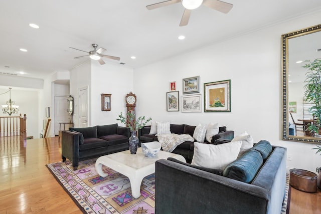 living room with hardwood / wood-style flooring, crown molding, and ceiling fan with notable chandelier