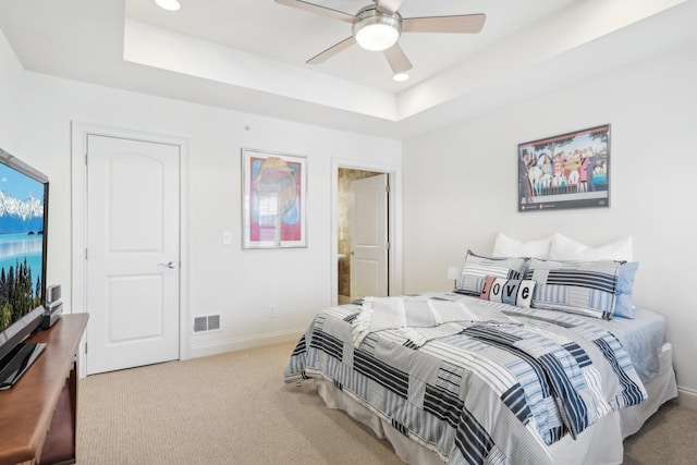 carpeted bedroom with a raised ceiling and ceiling fan