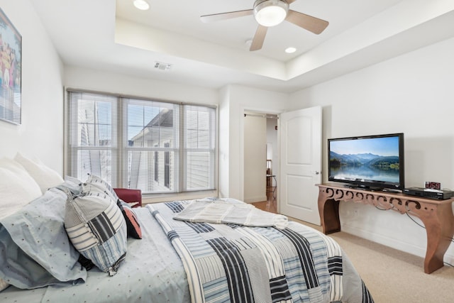 carpeted bedroom with a raised ceiling and ceiling fan