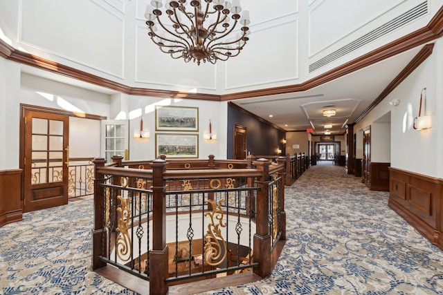 corridor with ornamental molding, a chandelier, a high ceiling, and carpet flooring