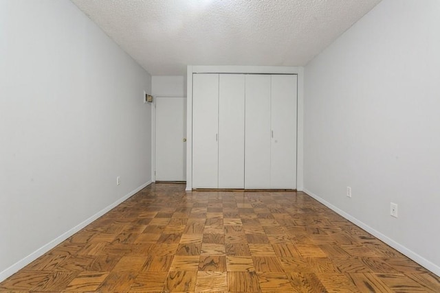 unfurnished bedroom with parquet flooring, a closet, and a textured ceiling