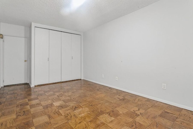 unfurnished bedroom with light parquet floors, a textured ceiling, and a closet