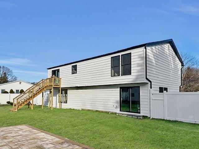 back of house featuring a wooden deck and a yard