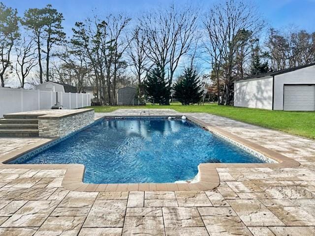 view of pool featuring a garage, an outbuilding, a patio, and a yard