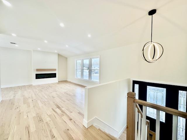 unfurnished living room featuring vaulted ceiling and light hardwood / wood-style floors