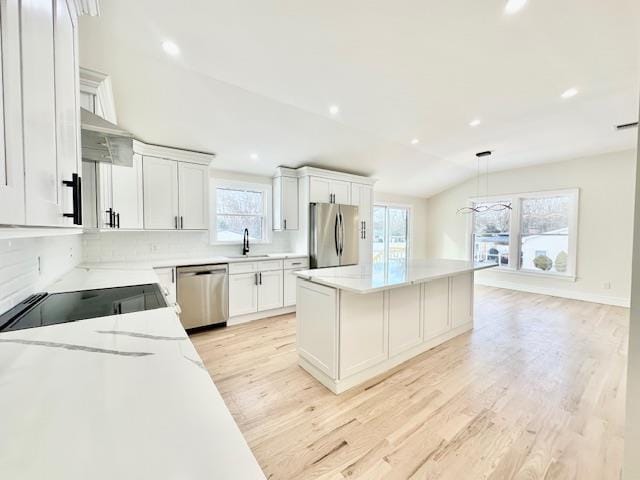 kitchen featuring appliances with stainless steel finishes, decorative light fixtures, sink, white cabinets, and light hardwood / wood-style floors