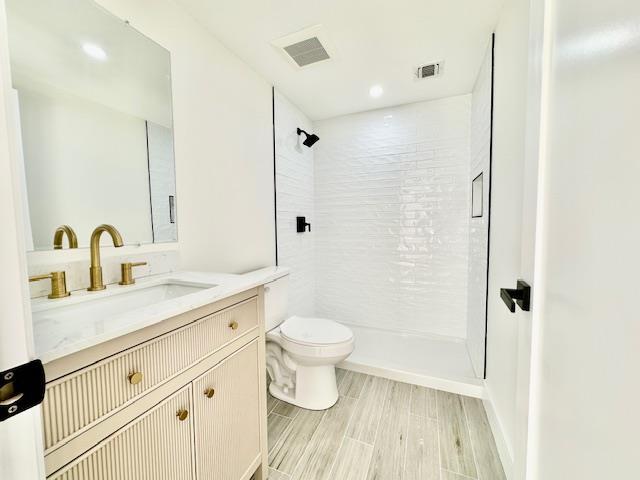 bathroom featuring tiled shower, vanity, and toilet