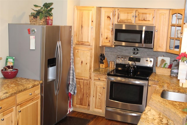 kitchen with backsplash, light brown cabinets, light stone countertops, and appliances with stainless steel finishes