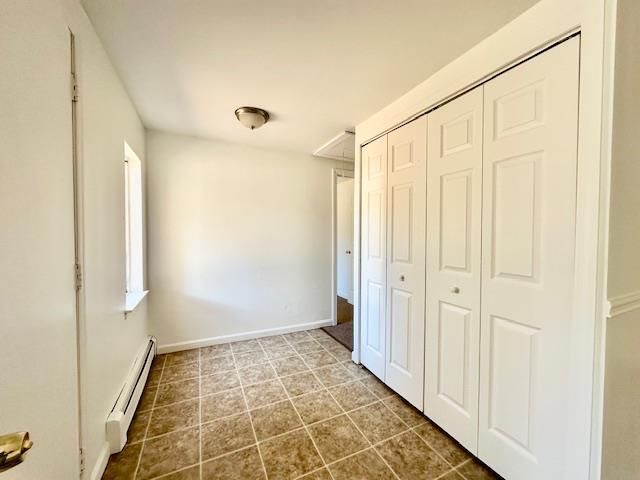 unfurnished bedroom with a baseboard radiator and a closet